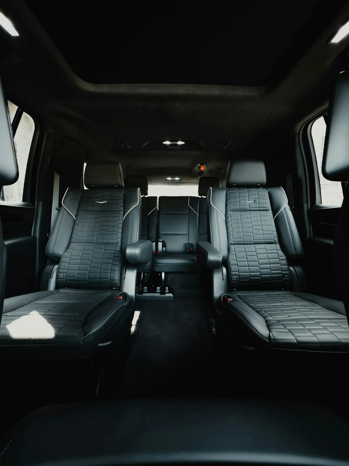 Representative Cadillac Escalade cabin with black leather captain’s chairs and a third-row bench; configuration varies by vehicle